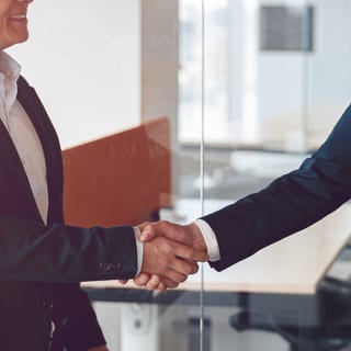 Two people shaking hands in an office.